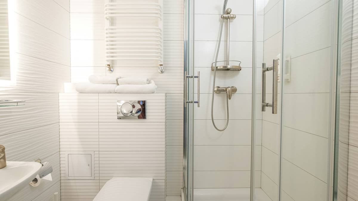 Diagram comparing swing radius of hinged vs. bifold shower doors showing bifold requires only 6 inches vs. 24+ inches